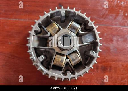 Eine detaillierte Ansicht eines mechanischen Metallgetriebes mit sichtbaren Rollen auf einer Holzoberfläche. Stockfoto