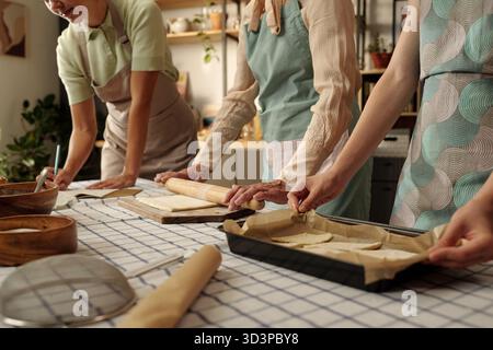 Drei weiße Frauen backen gemeinsam in der Küche Gebäck und bereiten Teig vor Stockfoto