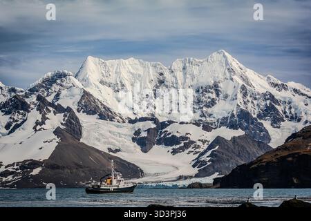 Unser Expeditionsschiff liegt am Fuße des spektakulären Zwillingsgipfels eines Eisbergs in der südöstlichen Ecke der Insel Südgeorgien im südlichen Ozean Stockfoto