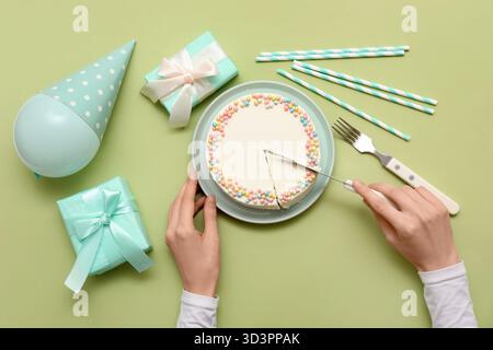 Frau, die süßen bento-Kuchen auf grünem Hintergrund schneidet Stockfoto