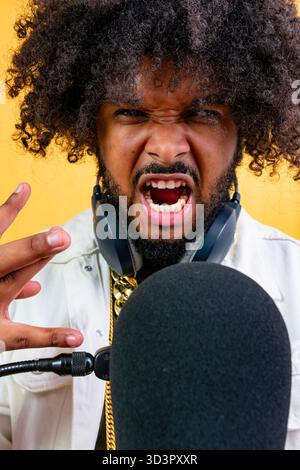 Wütender Mann, der in das Mikrofon schreit und Kopfhörer trägt Stockfoto