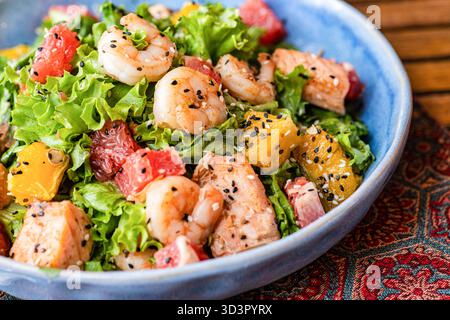 Ein lebendiger Salat mit Meeresfrüchten, frischen Garnelen und Lachs, Zitrusfrüchten und gemischtem Gemüse. Perfekt garniert mit Sesamsamen, ist dieses Gericht ein refr Stockfoto