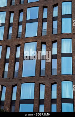 Das Bild zeigt eine moderne architektonische Fassade in Moskau mit großen reflektierenden Fenstern und eleganten Ziegelsteinen. Es hebt das städtische DE der Stadt hervor Stockfoto