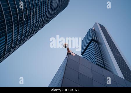 Flacher Blick auf moderne Wolkenkratzer im Cinco Torres, Madrid, Spanien, mit schlankem architektonischem Design und einer Überwachungskamera, die sich gegen einen Kleinen befindet Stockfoto