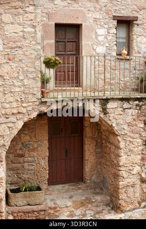 Eine charmante ländliche Fassade zeigt rustikale Steinmauern, eine hölzerne Balkontür und eine Bogentür in Mura, gelegen in Bages, Katalonien, Spanien. Die sc Stockfoto