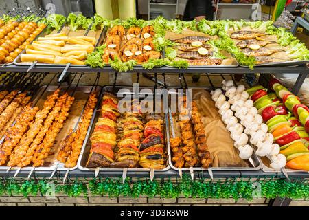 Köstliche Auswahl an Grillspießen vom Grill mit Fleisch, Gemüse und Meeresfrüchten. Das lebhafte Display zeigt perfekt gekochte Aromen für einen Stockfoto