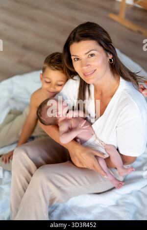 Eine liebevolle Großmutter umarmt ihre beiden kleinen Enkelkinder und schafft einen herzlichen Familienmoment voller Freude und Zuneigung Stockfoto