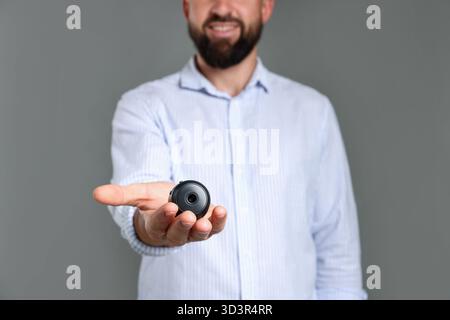 Mann mit versteckter Spionageskamera auf grauem Hintergrund, Nahaufnahme Stockfoto