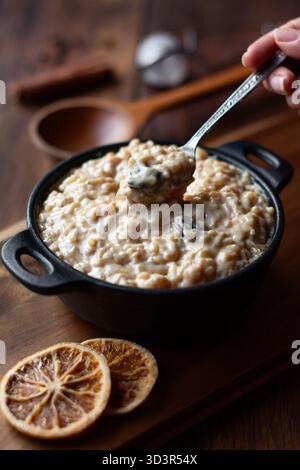 Cremiger peruanischer Reispudding, serviert in einer schwarzen Schüssel, garniert mit getrockneten Zitrusscheiben. Dieses traditionelle Dessert kombiniert Reis, Milch und Gewürze für Stockfoto