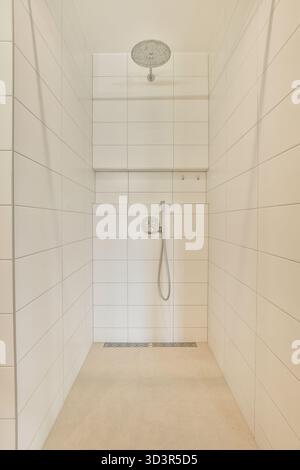Ein elegantes und makelloses Badezimmer mit weißen Fliesen und einer modernen Duschanlage, ideal für eine moderne häusliche Ästhetik. Stockfoto