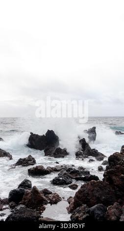Mächtige Ozeanwellen treffen auf zerklüftete Vulkangesteine im Badegebiet Negrito in Sao Mateus da Calheta auf der Insel Terceira auf den Azoren, Portugal, und schaffen so Stockfoto
