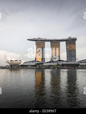 Singapur, Singapur - 5. Mai 2023: Blick auf die Marina Bay Sands schimmert in einem goldenen Farbton, der sich in den stillen Gewässern neben der futuristischen Form spiegelt Stockfoto
