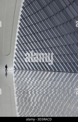 Chongqing, China - 13. Oktober 2025: Blick auf eine einsame Figur, die auf dem polierten Boden des Chongqing West Station läuft, das Licht wirft einen auffälligen Patte Stockfoto
