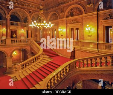 Budapest, Ungarn - 15. Oktober 2025: Blick auf die opulente Treppe mit rotem Teppichboden, die in der Ungarischen Staatsoper hinaufsteigt, im warmen Wasser getaucht Stockfoto