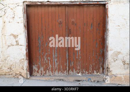 Rustikale Garagenszene, alte Holztür mit Schatten, Vintage Garagentor unter warmer Sonne, alte hölzerne Garagenfassade mit verblasster Farbe und weich Stockfoto