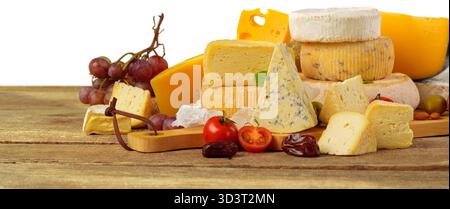 Verschiedene Käse- und Obstsorten auf einem Holzbrett in rustikaler Umgebung Stockfoto