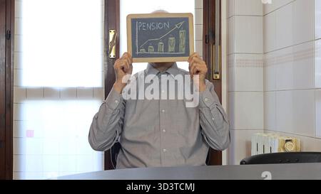 Eine Tafel mit dem Wort "Pension" drauf. Ein Mann, halblanges Porträt, hält eine Tafel vor seinem Gesicht. Stockfoto