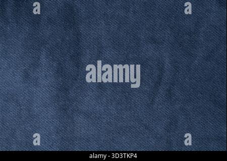 Nahaufnahme des dunkelblauen Denim-Materials mit seiner Textur und natürlichen Falten, perfekt für Modedesign und Textilanalyse. Stockfoto