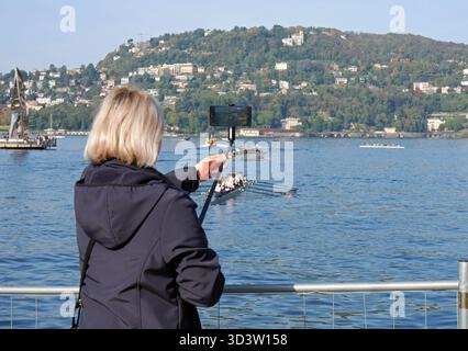 Frau, die ein Foto mit einem Selfie-Stick vor dem Comer See macht, Como, Italien Stockfoto