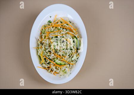 Frischer Weißkohl-Salat mit Karotten mit Olivenöl in einer Schüssel auf dem Tisch. Vertikale Draufsicht von oben. Hohe Qualität Stockfoto