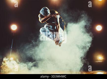 Junger Mann tanzt im Club mit Licht und Rauch. Tätowierung am Körper Stockfoto