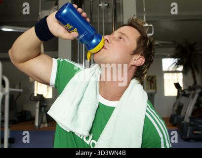 Mann im Fitnesscenter trinkt während des Trainings Stockfoto