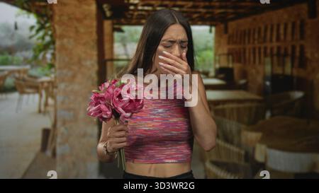 Frau mit Hand auf Brust auf der Restaurantterrasse drinnen, grimmend und den Mund bedeckt; Ekel bedauert. Stockfoto
