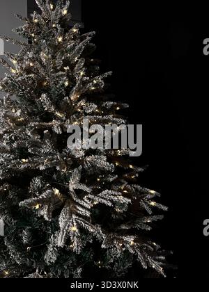 Künstlicher Weihnachtsbaum im Schnee mit gelben Lichtern Stockfoto