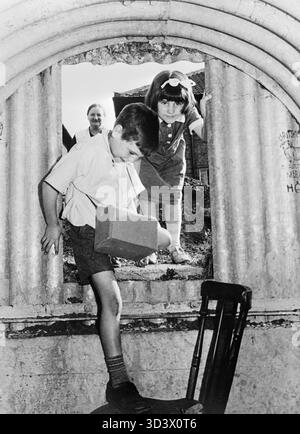 Doris und Alan Suter betreten den Anderson Luftschutzbunker in ihrem Garten an der 44 Edgeworth Road, Eltham, London, im Sommer 1940. Doris und Alan Suter treten zwischen Juni und August 1940 in das Anderson-Schutzhaus im Garten ihres Hauses in der 44 Edgeworth Road, Eltham, London, SE9. Ihre Mutter, Mrs. Suter, kann man hinter ihnen vor dem Tierheim sehen. Alan trägt seine Gasmasken-Kiste bei sich. Stockfoto
