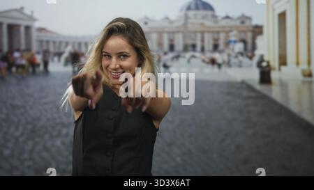 Frau zeigt mit dem Finger auf die Kamera mit beiden Händen im Quadrat auf den vatikan, lächelt und lehnt sich nach vorne; verspieltes Selbstvertrauen. Stockfoto