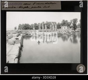 Ein Glasdiapositiv aus der Zeit um 1924-1932, das den südlichen Teil des Tempels von Montu in Medamud während einer Überschwemmung darstellt. Ein Arbeiter kann im überfluteten Bereich schwimmen sehen. Stockfoto