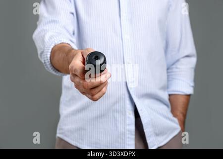 Mann mit versteckter Spionageskamera auf grauem Hintergrund, Nahaufnahme Stockfoto