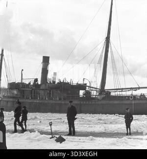 Ein Schiff wird im Winter um 1910 auf dem IJ River in Amsterdam, Niederlande, im Eis gefangen gesehen. Stockfoto