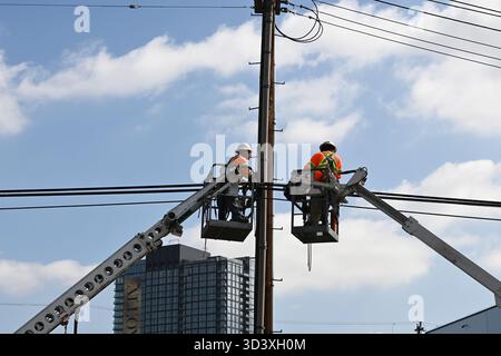 LOS ANGELES, KALIFORNIEN - 23. OCT 2025: Zwei Versorgungsarbeiter in separaten Cherry Pickern arbeiten an Stromleitungen. Stockfoto