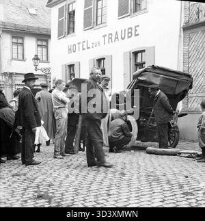 Eine Szene aus dem Jahr 1910, die einen Platten Reifen mit einer Menge Zuschauer im Hotel zur Traube zeigt. Der Standort kann Deutschland oder die Schweiz sein. Das Foto zeigt frühe Reiseschwierigkeiten im Auto. Stockfoto