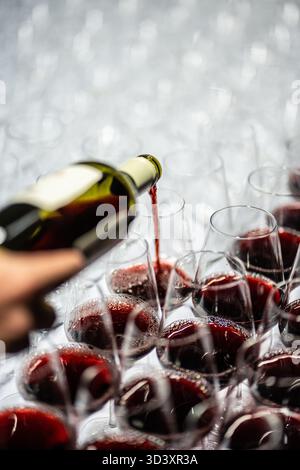 Geben Sie Rotwein von Hand in mehrere Gläser für eine Verkostung Stockfoto