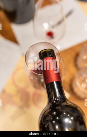 Rotwein, der aus einer Flasche in ein Glas gegossen wird, unterstreicht das Verkostungserlebnis Stockfoto