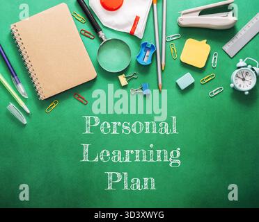 Verschiedene Schreibwaren, darunter ein Notizbuch, eine Lupe und eine Uhr, sind kunstvoll auf einem grünen Hintergrund angeordnet und schaffen so ein einladendes atmos Stockfoto