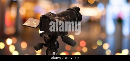 Professionelle Kamera vor verschwommenem Hintergrund mit Bokeh-Lichtern. Bannerdesign Stockfoto