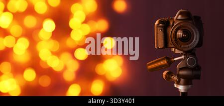 Professionelle Kamera gegen verschwommenes Licht auf dunklem Hintergrund, Bokeh-Effekt. Bannerdesign Stockfoto