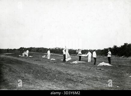 Mitglieder des Königlich Niederländischen Verteidigungsverbands „Volksweerbaarheid“ legen ihre Betten im Freien in einem Lager in Laren, Niederlande, 1912. Stockfoto