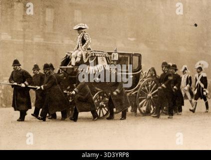 Bei der Eröffnung des britischen Parlaments 1913 gingen die Pferde, die die Kutsche des deutschen Botschafters zogen, wild. Die Pferde wurden angehalten, aber die Kutsche wurde schwer beschädigt und musste von Polizisten gezogen werden. Diese Veranstaltung fand in London, England, statt. Stockfoto