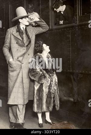 Der höchste Mann aus den USA, der sich mit einer durchschnittlich großen Frau in einem Pelzmantel an ein Zugabteil lehnt. Dieses Foto wurde 1920 in Hollywood, USA, aufgenommen. Stockfoto