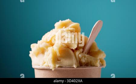 Gelbes Mango- und Ananassorbet in Papierbecher auf buntem Hintergrund, Lebensmittelnähe Stockfoto