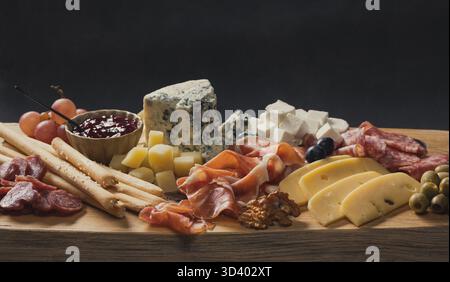 Set mit verschiedenen Fleisch- und Käsesnacks auf hölzernem Schneidebrett, Nahaufnahme von Delikatessen, die für eine Party serviert werden Stockfoto