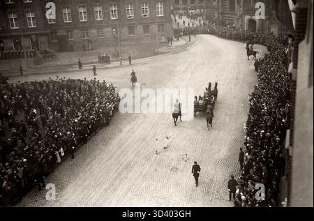 Königin Wilhelmina (1880–1962) kommt mit einer Pferdekutsche am Damplatz an. Eine königliche Umgebung und eine große Zuschauermenge versammeln sich, um ihren Pass zu sehen, mit dem Nieuwe Kerk auf der rechten Seite und dem Königspalast auf der linken Seite, Amsterdam, 1921. Stockfoto