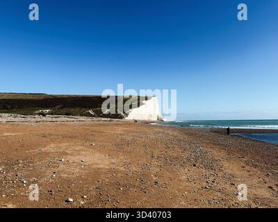 Küstenszene in East Sussex mit weißen Kreidefelsen, Sandstrand und ruhigem Meer unter einem klaren blauen Himmel. Stockfoto