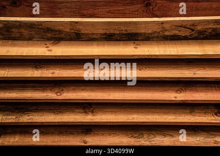 Dunkle, kräftige Holzdielen, horizontal gestapelt, schaffen einen rustikalen strukturierten Hintergrund. Stockfoto