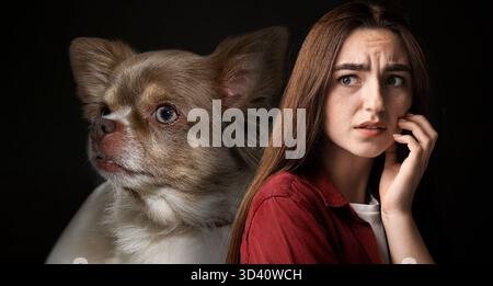 Verängstigte Frau, die an Zynophobie leidet, schwarzer Hintergrund. Pathologische Angst bei Hunden Stockfoto