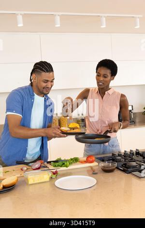 Kochen Sie verschiedene Paare, die Gemüse auf der Insel in moderner Küche mit Kochmesser zubereiten Stockfoto